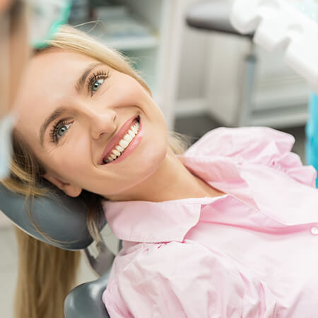 A woman in the dental office lying in the dentist's chair while smiling