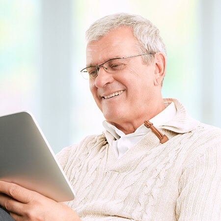 A mature man smiling while looking at his tablet