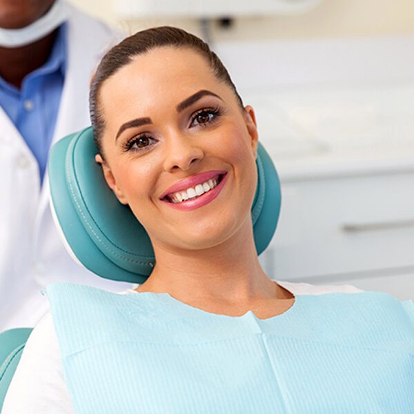A woman sitting in the dentist's chair while smiling