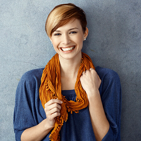 A red haired woman smiling while wearing a scarf