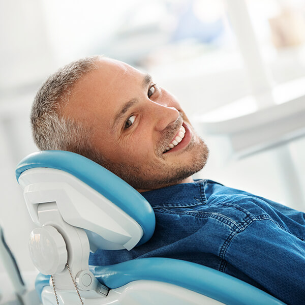 A man lying in the dentist's chair while smiling